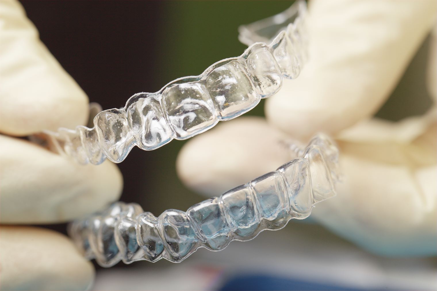invisalign-chandler-az A picture of a doctor at Smiles Chandler holding a sest of Insvisalign Aligners wearing white nitrile gloves